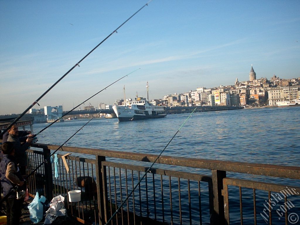 View of fishing people, a landing ship, Galata Bridge and Galata Tower from the shore of Eminonu in Istanbul city of Turkey.
