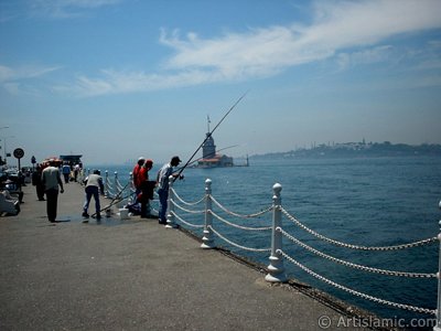 View of fishing people and Kiz Kulesi (Maiden`s Tower) from Uskudar shore of Istanbul city of Turkey. (The picture was taken by Artislamic.com in 2004.)
