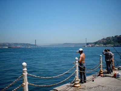 View of fishing people and on the horizon Bosphorus Bridge from Uskudar shore of Istanbul city of Turkey. (The picture was taken by Artislamic.com in 2004.)