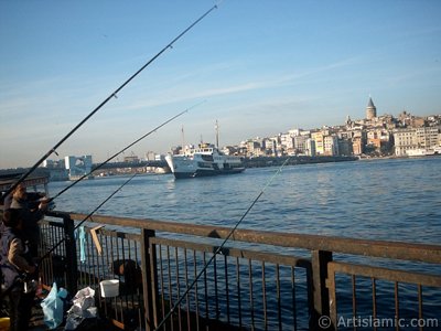 View of fishing people, a landing ship, Galata Bridge and Galata Tower from the shore of Eminonu in Istanbul city of Turkey. (The picture was taken by Artislamic.com in 2004.)