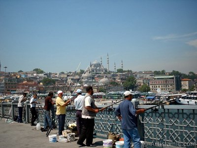 View of fishing people, at far behind Suleymaniye Mosque and below Rustem Pasha Mosque from Galata Bridge located in Istanbul city of Turkey. (The picture was taken by Artislamic.com in 2004.)