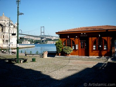 View of the jetty, Bosphorus Bridge, Ortakoy Mosque and the moon seen in daytime over the bridge`s legs from Ortakoy shore in Istanbul city of Turkey. (The picture was taken by Artislamic.com in 2004.)