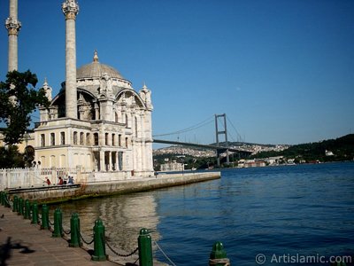 View of Bosphorus Bridge, Ortakoy Mosque and the moon seen in daytime over the bridge`s legs from Ortakoy shore in Istanbul city of Turkey. (The picture was taken by Artislamic.com in 2004.)