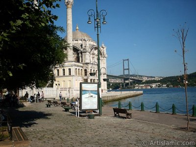 View of Bosphorus Bridge, Ortakoy Mosque and the moon seen in daytime over the bridge`s legs from Ortakoy shore in Istanbul city of Turkey. (The picture was taken by Artislamic.com in 2004.)