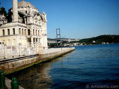 View of Bosphorus Bridge, Ortakoy Mosque and the moon seen in daytime over the bridge`s legs from Ortakoy shore in Istanbul city of Turkey. (The picture was taken by Artislamic.com in 2004.)