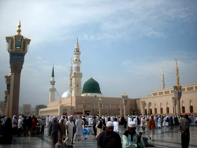 The Prophet Muhammad`s (saaw) Mosque (Masjed an-Nabawe) in Madina city of Saudi Arabia and the muslims going out of mosque after a prayer time. On the area under the green dome there are tombs of the Prophet Muhammad, Abubakr (first caliph of Islam) and Omar (second caliph). At the same time there is home and minbar of the Prophet and ``soffa`` where the poor muslims used to stay and take education in the time of the Prophet. (The picture was taken by Mr. Mustafa one of the visitors of Artislamic.com in 2003 Ramadan.)