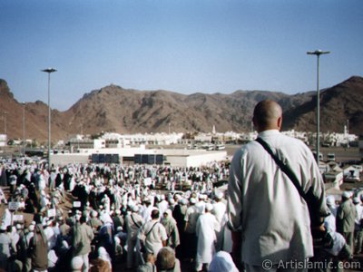 The Mounts Uhud, the field of Battle of Uhud (the second battle of the Prophet Muhammad [saaw] against unbelievers); the cemetery of the first muslims died for Islam during the Battle of Uhud (located in the middle) and the pilgrims visiting these places in Mecca city of Saudi Arabia. (The picture was taken by Mr. Mustafa one of the visitors of Artislamic.com in 2003 Hajj season.)