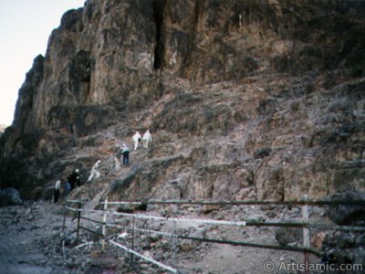 The cave located in the skirt of the Mount Uhud and the pilgrims climbing it. It is reported that when the Prophet Muhammad (saaw) was wounded during the Battle of Uhud, He had climbed into this cave and treated in it. (Sources of the event: Ibn Hisham, p.572-576; Muhammad Hamidullah, Battles of The Prophet [in Turkish: Hz. Peygamber`in Savaslari], p.70, par.106; Muhammad Hamidullah, Le Prophte de l`Islam, par. 391.) (The picture was taken by Mr. Mustafa one of the visitors of Artislamic.com in 2003 Hajj season.)