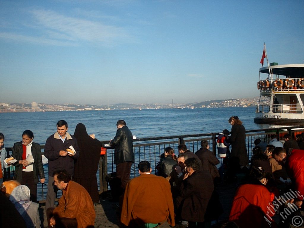 View of people eating sandwich with fish from the shore of Eminonu in Istanbul city of Turkey.

